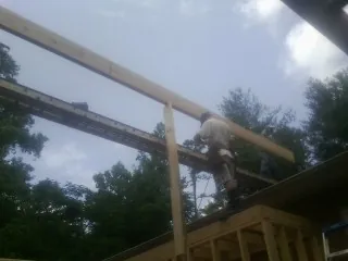 Carpenter setting a ridge beam over a new addition frame — Ice Dam Removal by Roofing Brothers in New Bern