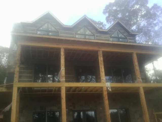 Dormers and porch framing on a large log home under construction — Roof Coating work by our crew in New Bern