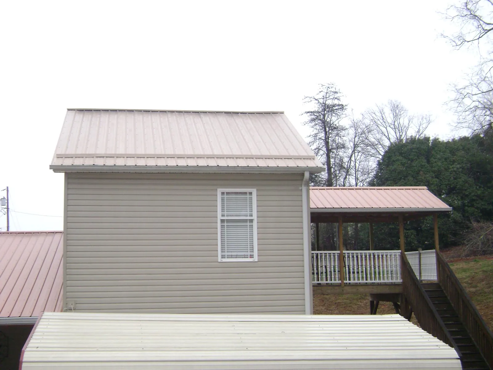 Tan metal roofs on a two story addition and attached porch, from a Roof Replacement job in New Bern