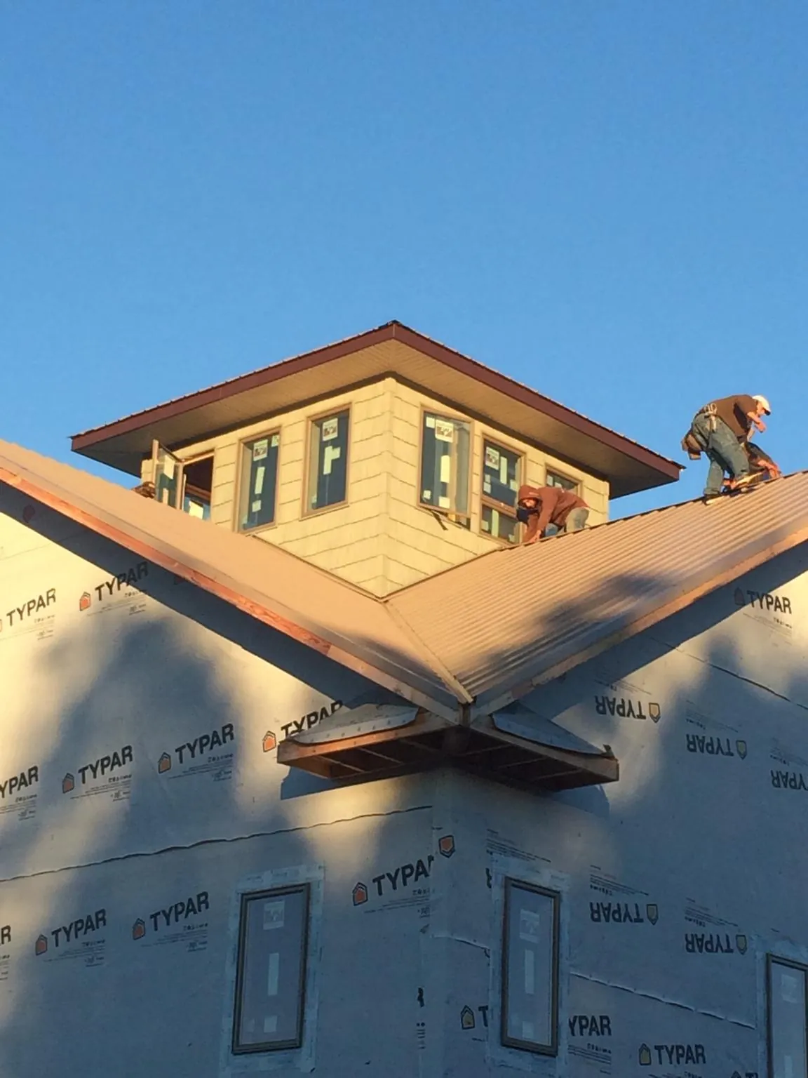 Roofers working around a rooftop cupola on a new metal roof at sunset — Roof Waterproofing in New Bern by Roofing Brothers